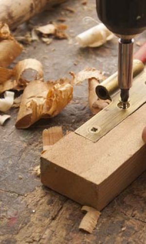 close up  of a carpenter screwed a hinge on a wooden plank